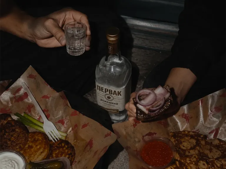 Late-night spread: draniki, house pickles, rye toast with red onion and salo, blini with red caviar, and a shot of vodka. Client-provided photography.